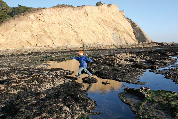 Child jumping over tidepool