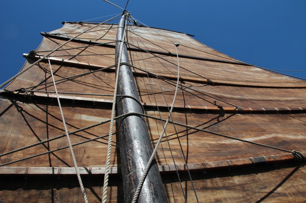 Old Chinese shrimping boats relied on a single sail, like the one above. The horizontal wooden beams allow crew members to adjust the sail’s size as winds change. Ethan Bien.   