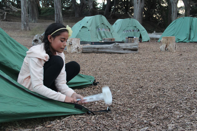 Sixth grader Wendy Mejia secures her tent before nightfall on a school camping trip in the Presidio. (Photo by Rachel Hiles)