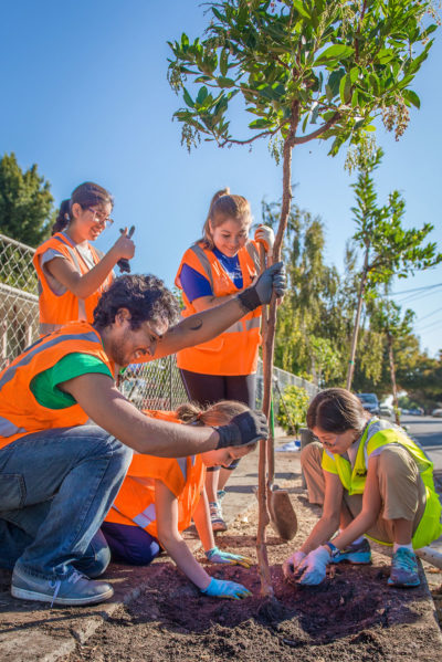 Uriel Hernandez guides a team from Girls' Middle School in planting a madrone in the Beech Street neighborhood of East Palo Alto in October 2015. (Photo by Federica Armstrong, courtesy of Canopy)